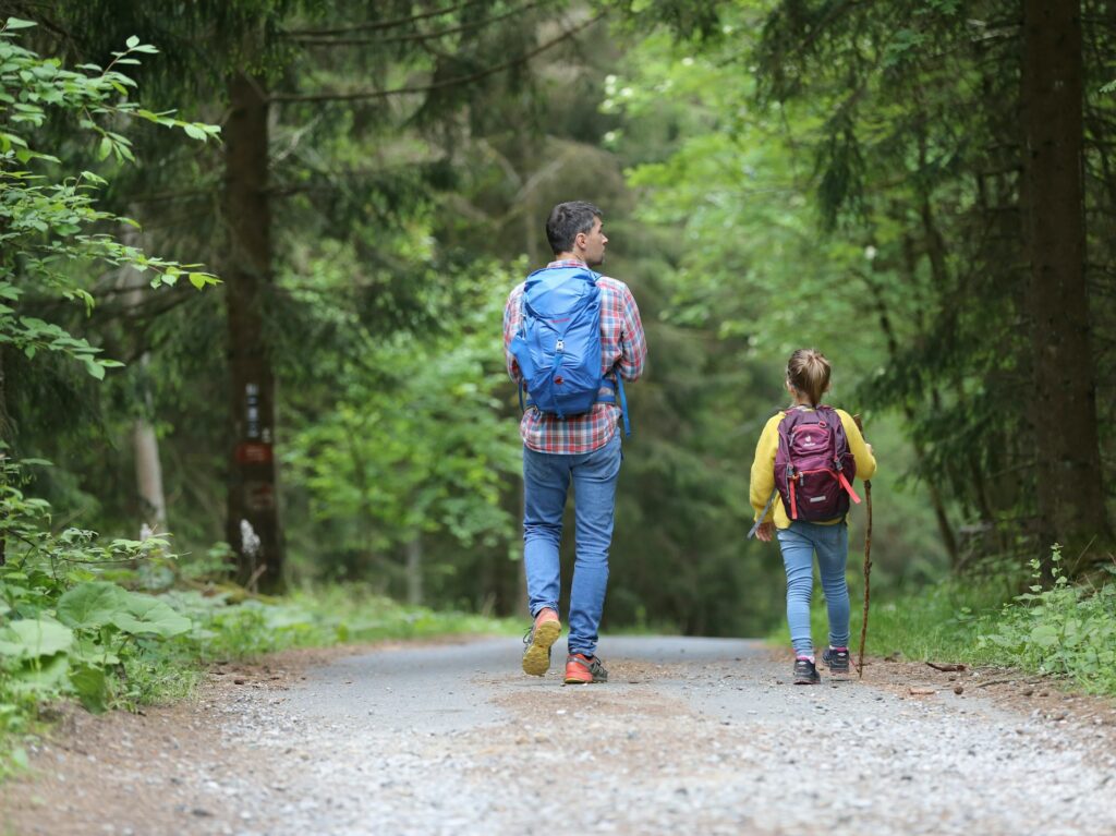 Father and daughter hiking on a gravel forest path