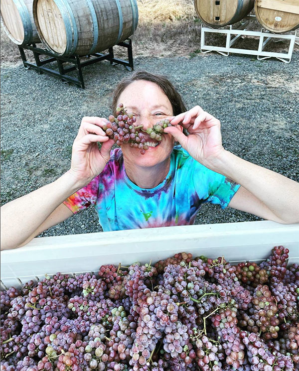 Smiling woman holding grapes in front of her face