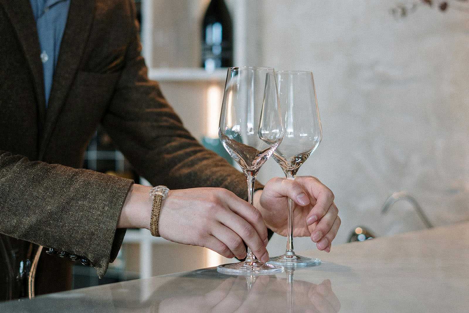 tasting room associate placing empty wine glasses on bar